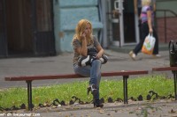 девушка в джинсах на каблуках сидит на улице